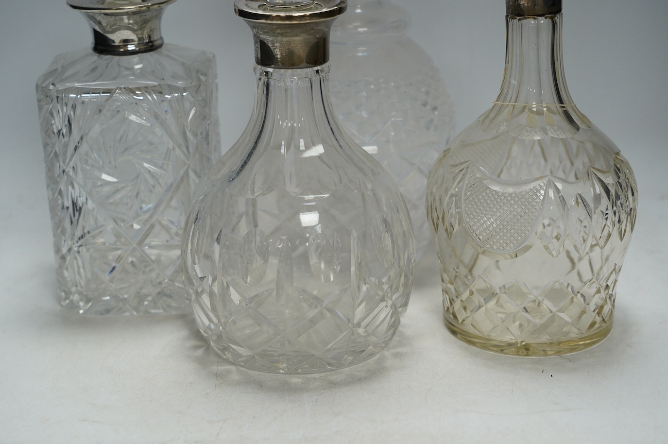 Four silver mounted glass decanters and stoppers, largest 29cm high. Condition - fair to good, one diseased